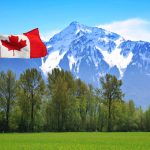 Canadian flag in front of te snow capped Rocky Mountains, British Columbia, Canada.