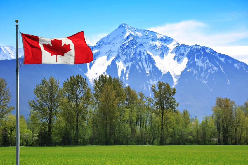 Canadian flag in front of te snow capped Rocky Mountains, British Columbia, Canada.
