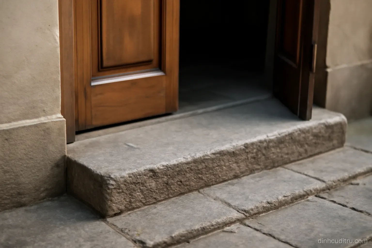 a solid stone doorstep at the entrance of a building with the door standing open